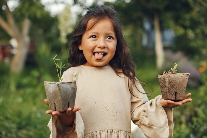 Child holding two potted saplings in both hands