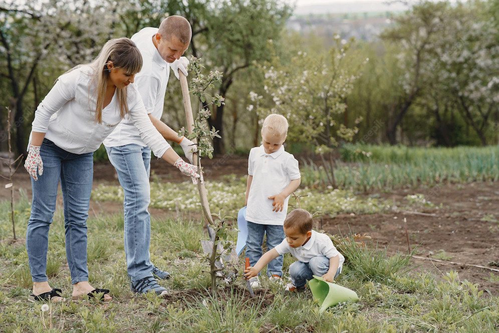Two adults and two children planting a young tree with a shovel